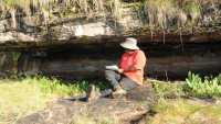 Photo of speaker, Catherine Namono, on a rock during her research